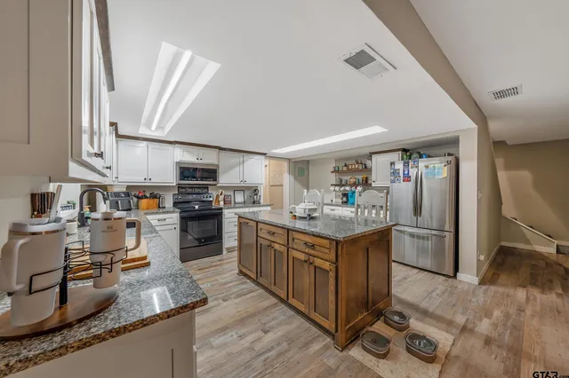 a large kitchen with stainless steel appliances granite countertop a stove refrigerator and a sink