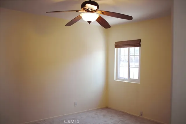 an empty room with chandelier fan and windows