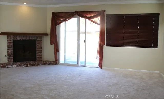 a view of an empty room with a fireplace and a window