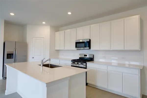 a kitchen with stainless steel appliances a white stove top oven a sink a refrigerator and white cabinets