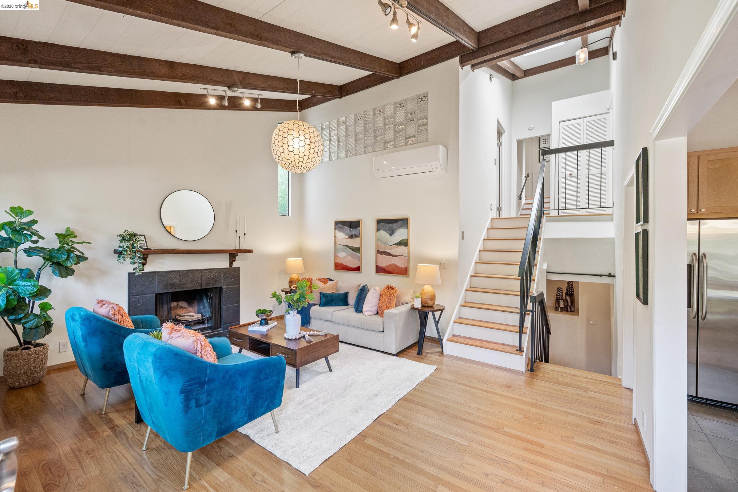 6600 Heather Ridge Way Oakland, CA 94611 - Photo 14 of 66 Spacious living area featuring exposed beam ceilings, wood-finish flooring, and a tiled fireplace hearth