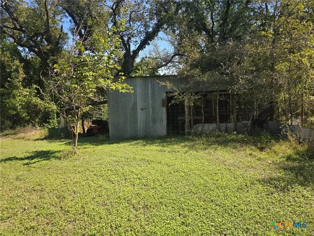 a backyard of a house with lots of plants and large trees