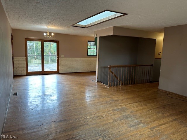 160 Arends Ridge Road Marietta, OH 45750 - Photo 8 of 19 Empty room featuring hardwood / wood-style flooring, a textured ceiling, a notable chandelier, and a skylight