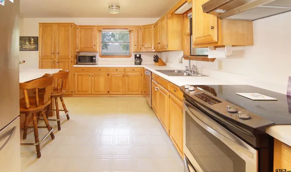 a view of a kitchen with kitchen island a large window a sink and a counter space
