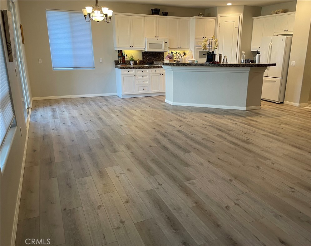 a kitchen with stainless steel appliances granite countertop a sink dishwasher a refrigerator cabinets and wooden floor
