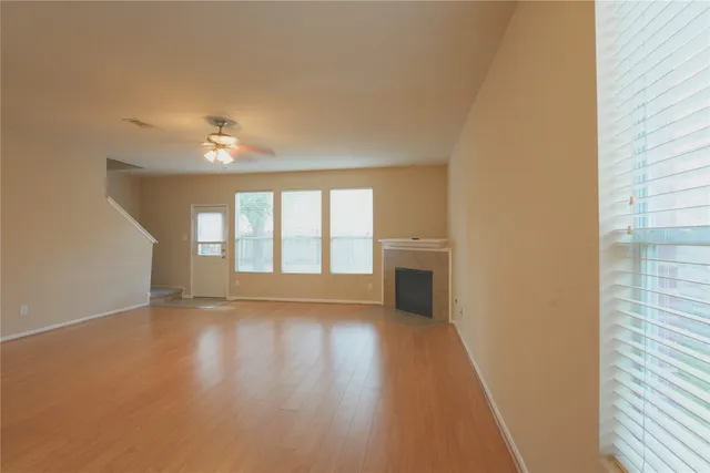 a view of an empty room with a window and wooden floor