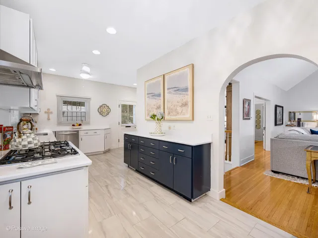 a kitchen with stainless steel appliances granite countertop a stove a sink a refrigerator and white cabinets with wooden floor