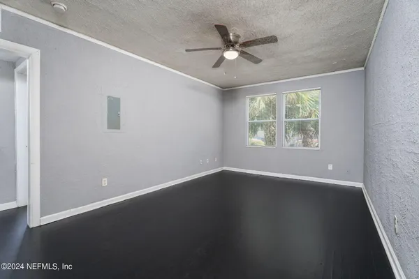 an empty room with wooden floor chandelier fan and windows