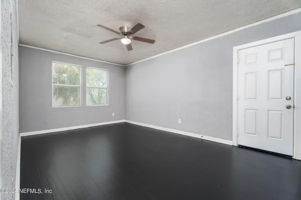 an empty room with wooden floor chandelier fan and windows