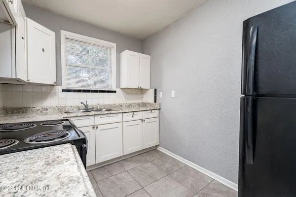 a kitchen with granite countertop a sink stove and refrigerator