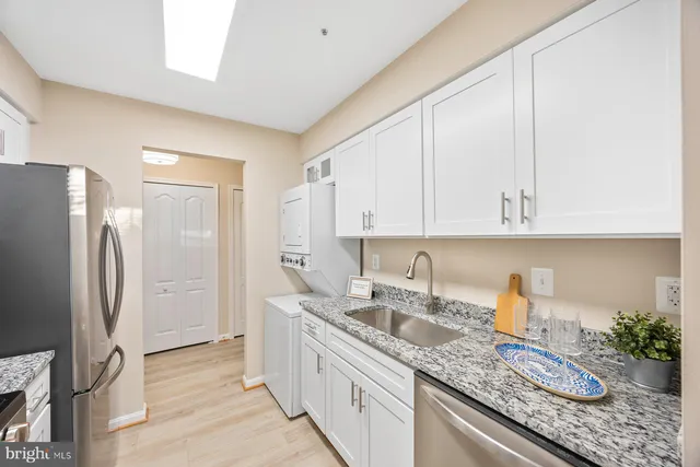a kitchen with granite countertop a sink a refrigerator and cabinets