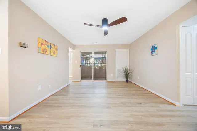 a view of an empty room with a window and wooden floor