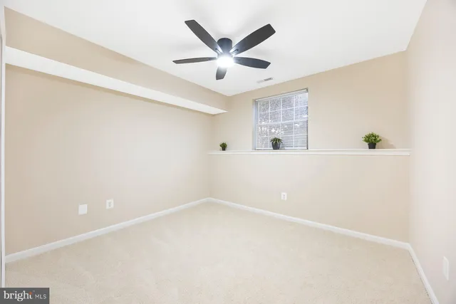an empty room with window and ceiling fan