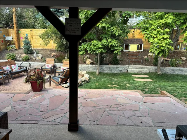 a view of a patio with table and chairs potted plants and large tree