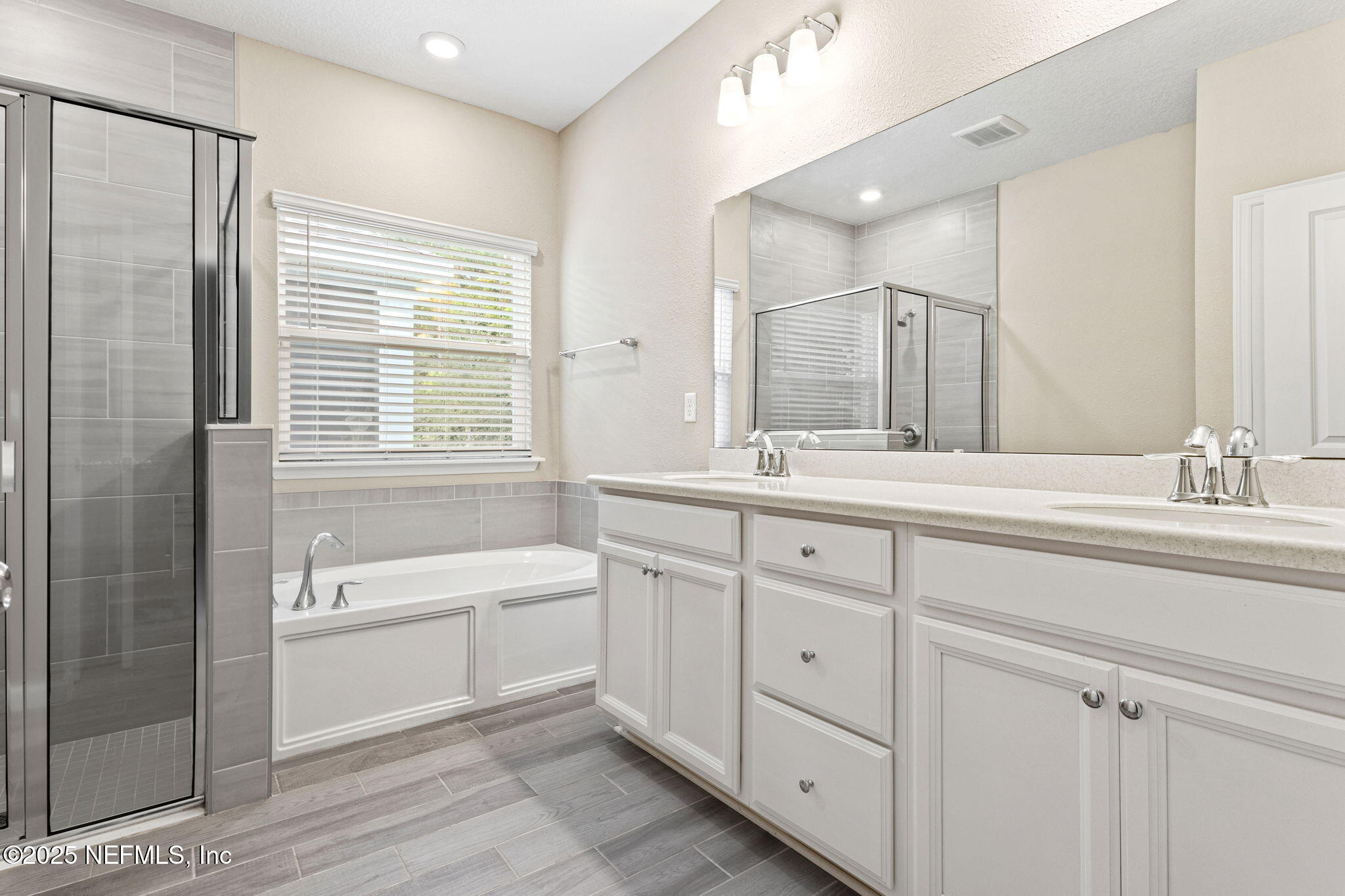 911 Colon Lane Jacksonville, FL 32218 - Photo 15 of 32 a bathroom with a double vanity sink a large mirror and a bathtub