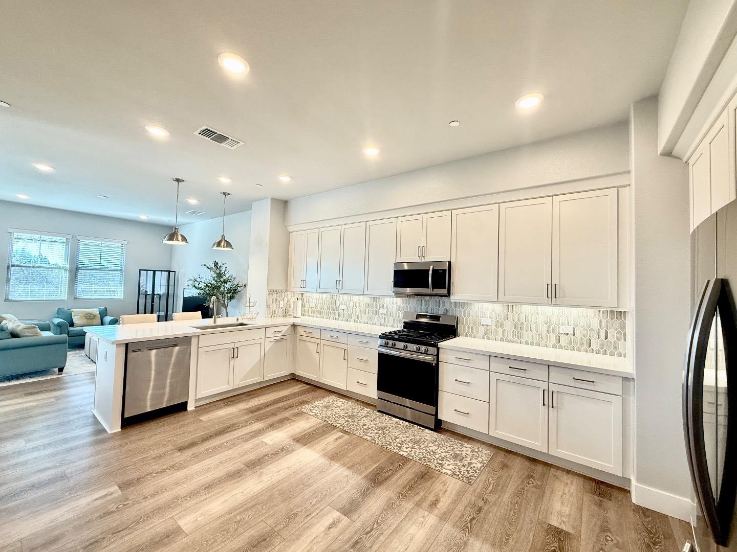 1661 Spring Street, Unit 424 Davis, CA 95616 - Photo 8 of 34 a large kitchen with stainless steel appliances granite countertop a stove top oven a sink a refrigerator white cabinets and wooden floor