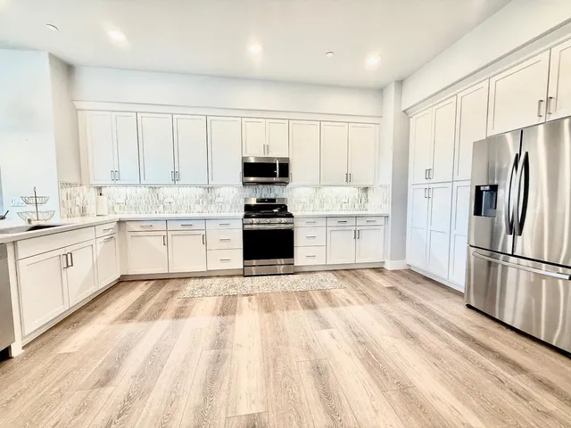a kitchen with white cabinets and stainless steel appliances