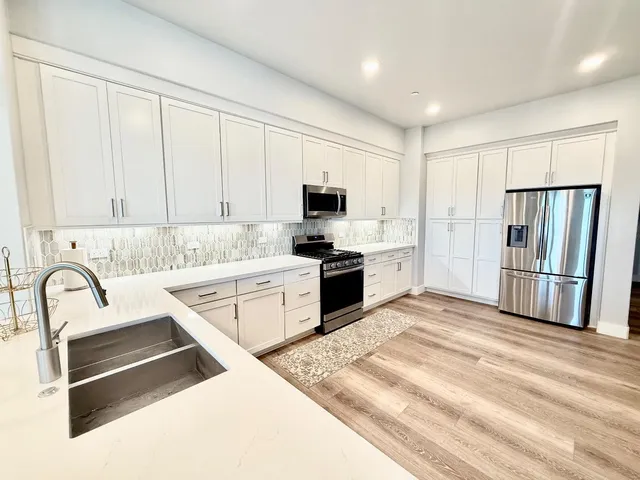 a kitchen with granite countertop a refrigerator sink and cabinets