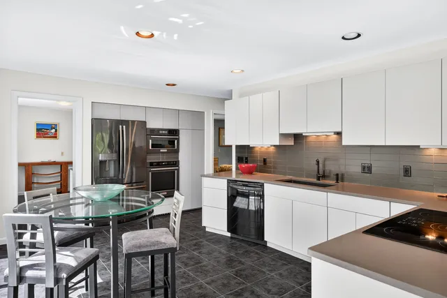 a kitchen with stainless steel appliances a table and chairs in it
