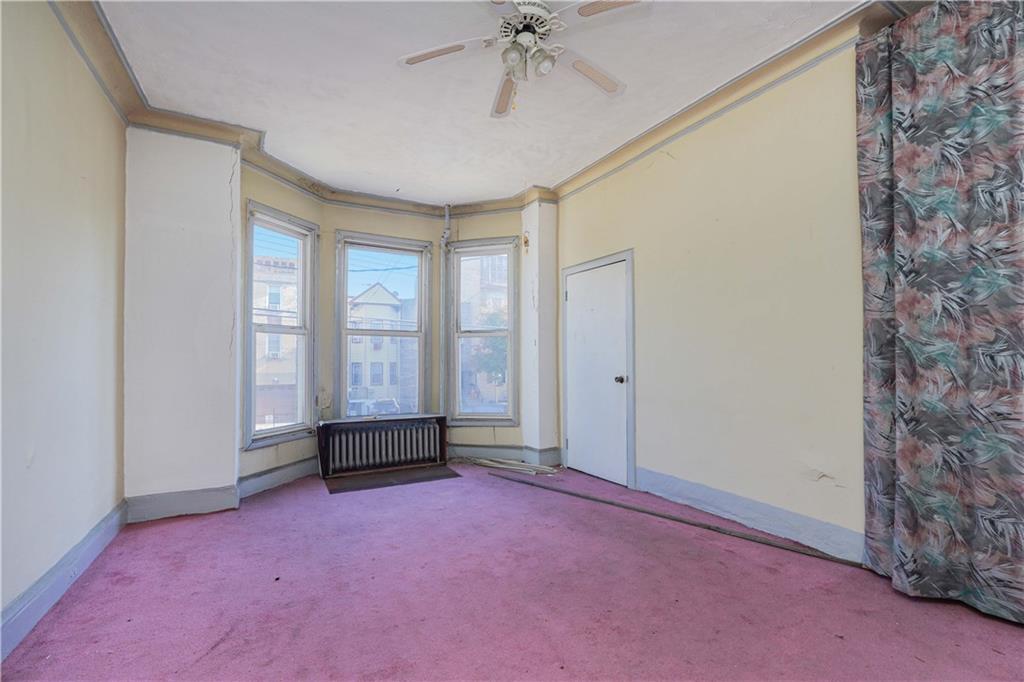 1122 39th Street Brooklyn, NY 11218 - Photo 6 of 27 an empty room with chandelier fan and windows