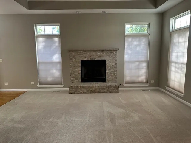 an empty room with windows and fireplace