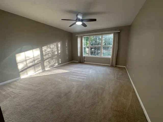 en empty room with windows and ceiling fan