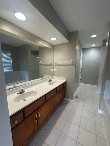 a spacious bathroom with a double vanity sink a mirror and a