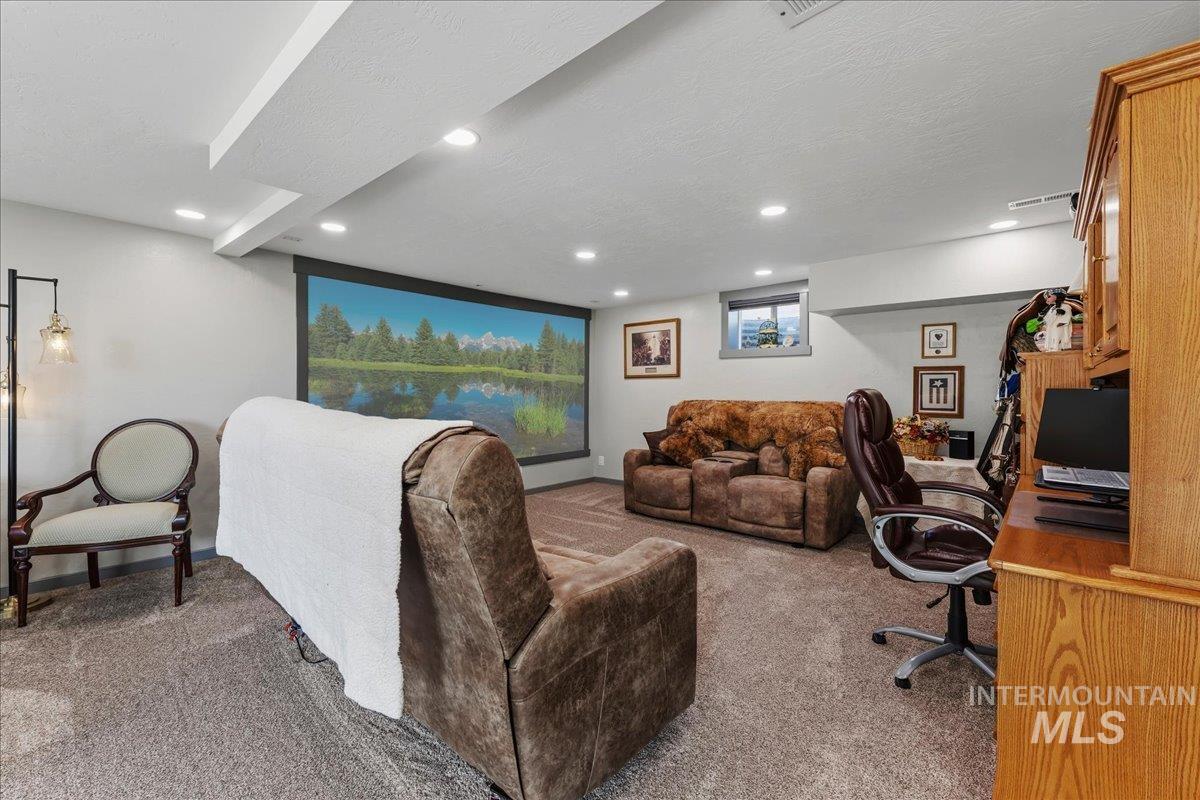 6323 Foothill Road Star, ID 83669 - Photo 14 of 50 Spacious carpeted room featuring a large projection screen, recessed lighting, and a built-in wooden office hutch with glass-fronted upper cabinets