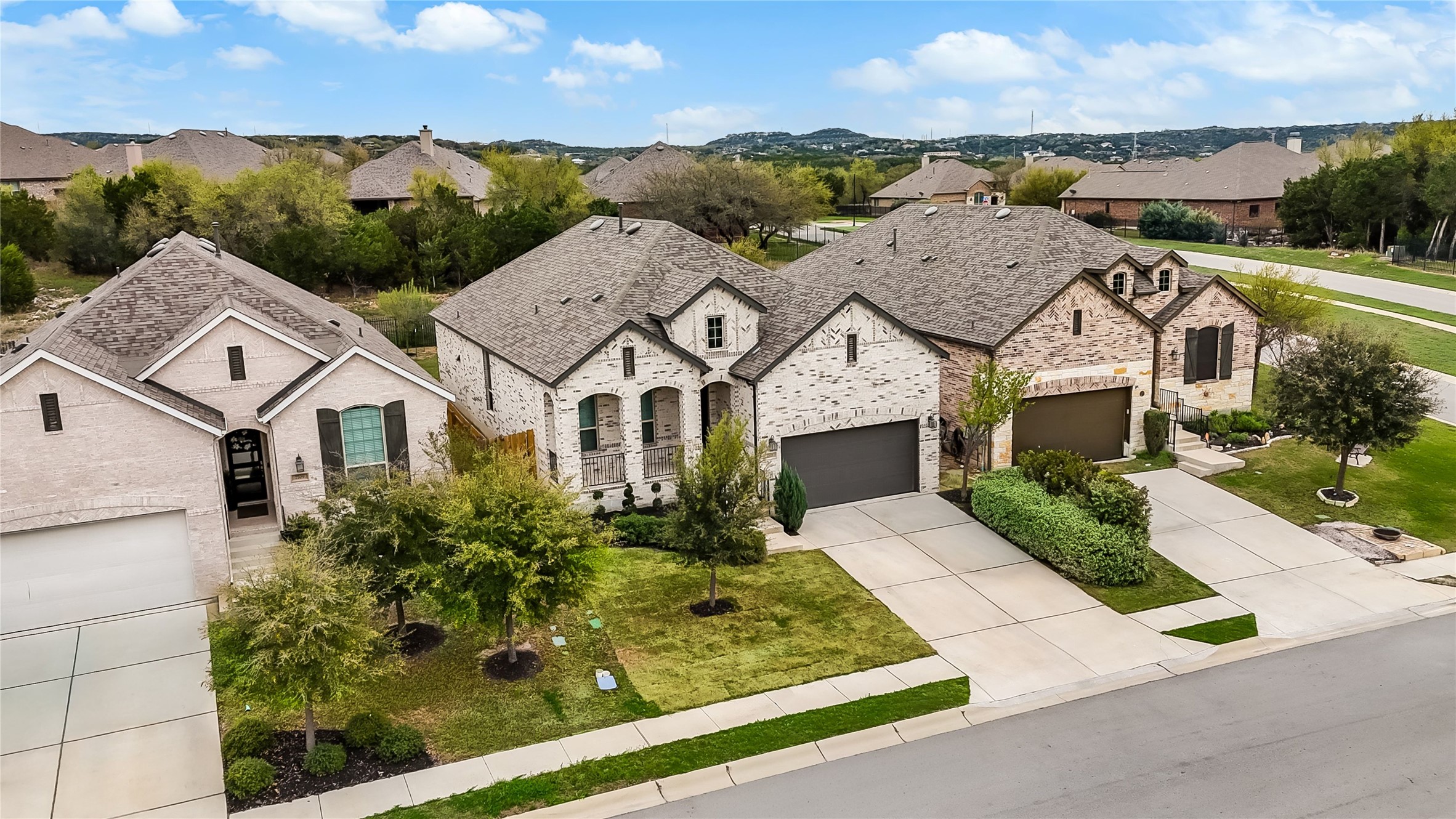 7705 Pace Ravine Drive Lago Vista, TX 78645 - Photo 27 of 40 French country home with concrete driveway, stone siding, a residential view, an attached garage, and a front lawn