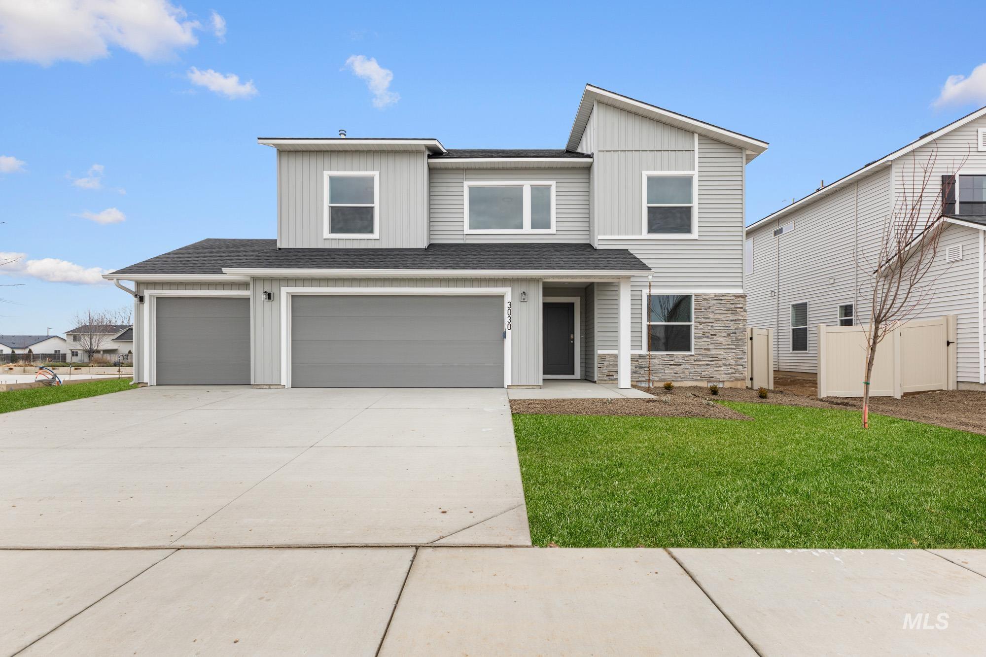 View of front of property featuring a shingled roof, stone siding, concrete driveway, a front yard, and a garage