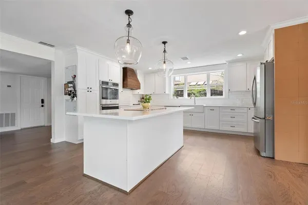 a kitchen with white cabinets stainless steel appliances and window