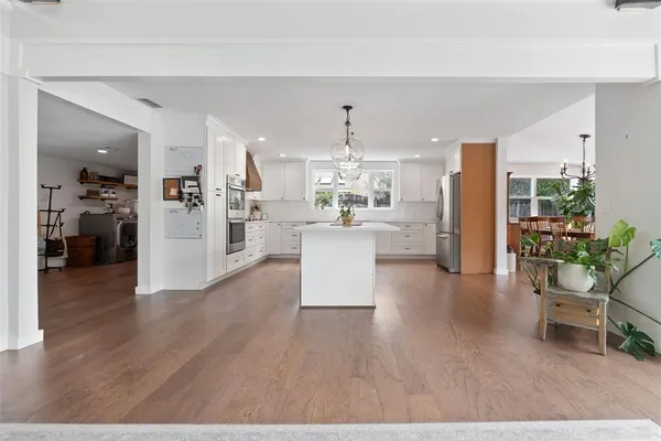 a kitchen with stainless steel appliances a refrigerator a stove a sink dishwasher a oven with white cabinets and wooden floor