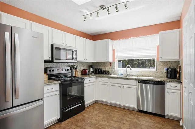 a kitchen with granite countertop a sink stainless steel appliances and cabinets