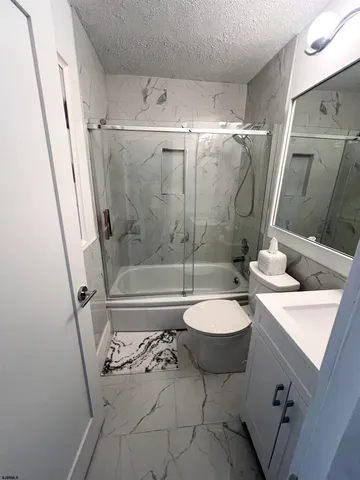 a bathroom with a granite countertop sink toilet a mirror and shower