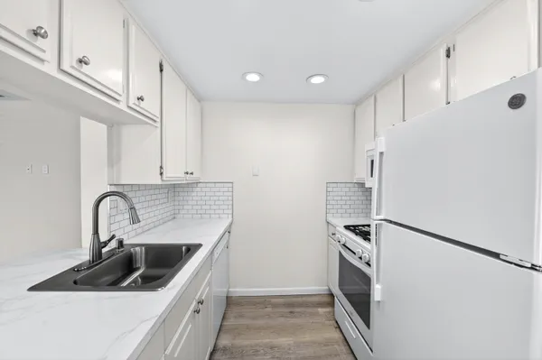 a kitchen with a sink a refrigerator and cabinets