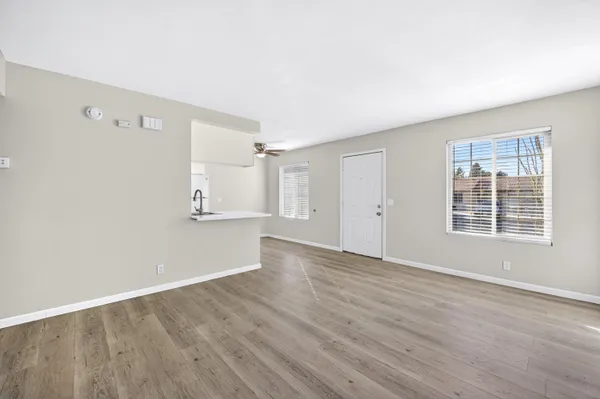 an empty room with wooden floor cabinet and windows