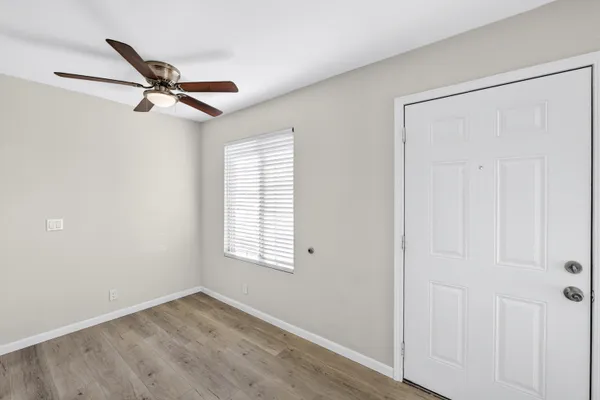 an empty room with windows and fan