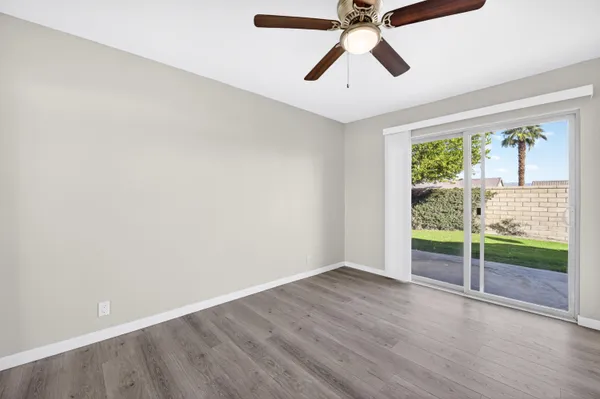 an empty room with wooden floor fan and windows