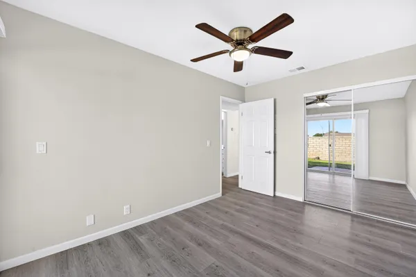 an empty room with wooden floor and a ceiling fan