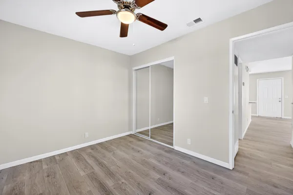 an empty room with wooden floor a ceiling fan and a fan