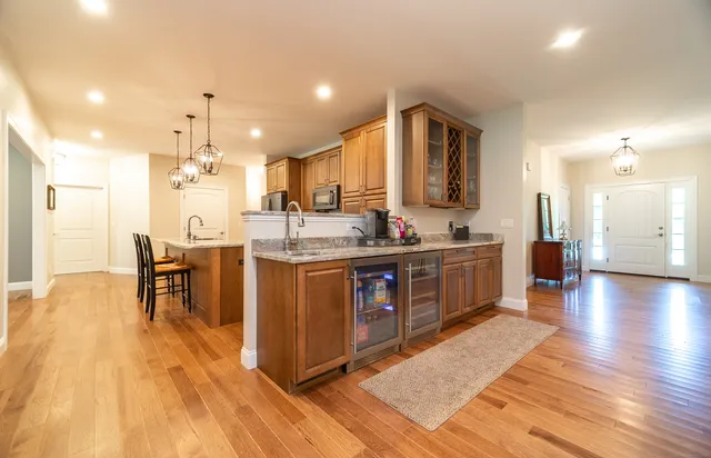 a kitchen with stainless steel appliances granite countertop a stove a sink a refrigerator and a dining table with wooden floor