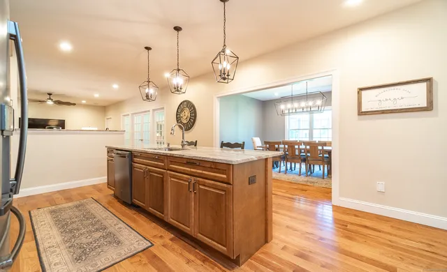 a large kitchen with stainless steel appliances granite countertop a stove a sink a refrigerator and a dining table with wooden floor