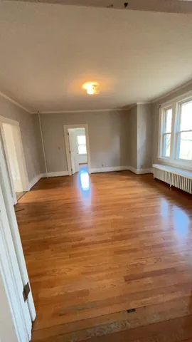 a view of an empty room with window and wooden floor