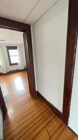 a view of hallway with window and wooden floor