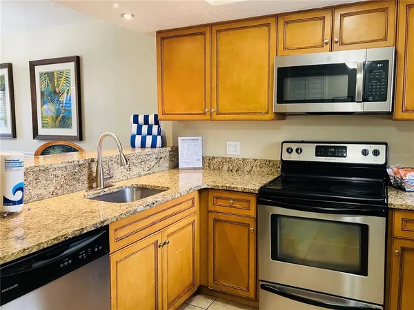 a kitchen with granite countertop a stove sink and microwave