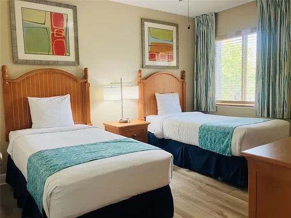 a bedroom with two beds and wooden floor