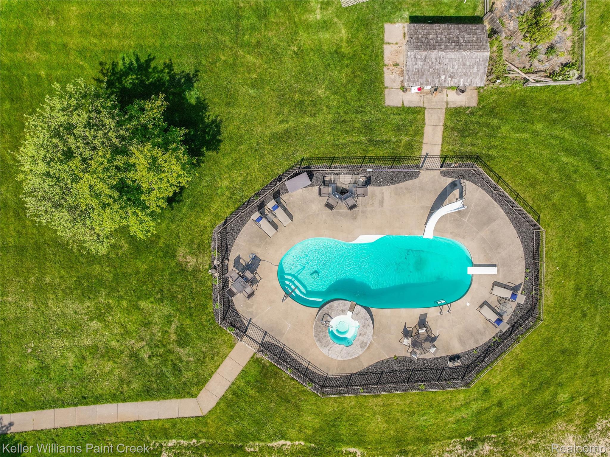 5813 36 Mile Road Romeo, MI 48065 - Photo 68 of 81 Fenced swimming pool area featuring a kidney-shaped pool with a slide and diving board, an integrated circular hot tub, and concrete patio surround