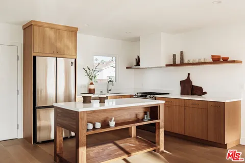 a kitchen with stainless steel appliances a dining table chairs refrigerator and sink