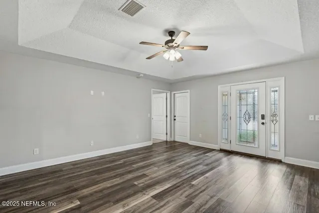 an empty room with wooden floor fan and windows