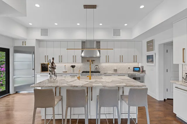 a kitchen with kitchen island granite countertop a dining table chairs cabinets and stainless steel appliances